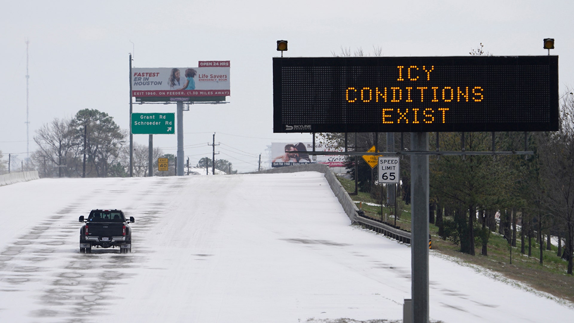 A truck drives past a highway sign Monday, Feb. 15, 2021, in Houston. A frigid blast of winter weather across the U.S. plunged Texas into an unusually icy emergency Monday that knocked out power to more than 2 million people and shut down grocery stores and dangerously snowy roads.