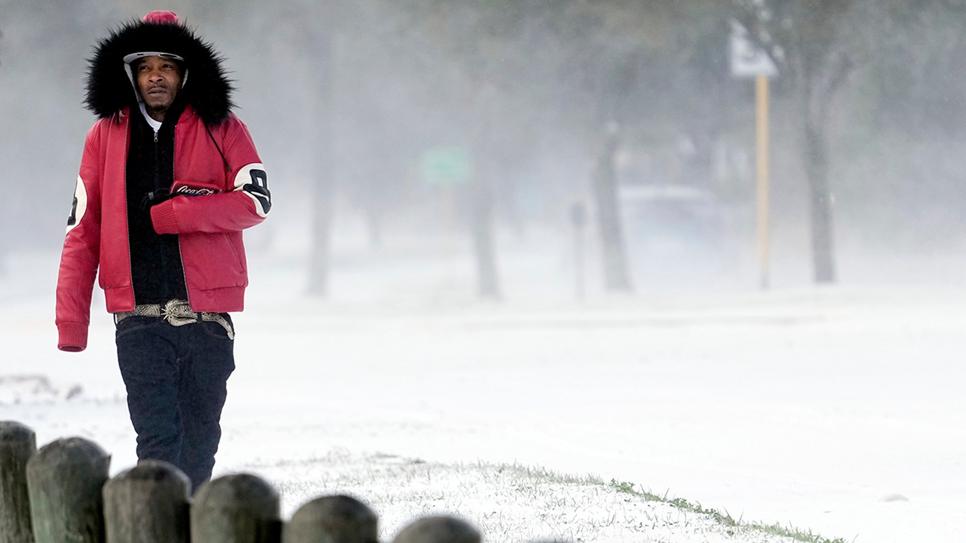 Igee Cummings walks through the snow Monday, Feb. 15, 2021, in Houston. A winter storm dropping snow and ice sent temperatures plunging across the southern Plains, prompting a power emergency in Texas a day after conditions canceled flights and impacted traffic across large swaths of the U.S.