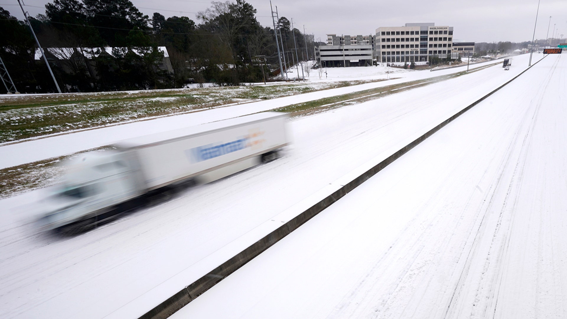 An 18-wheeler speeds along an ice covered Interstate 55 in north Jackson, Miss., Monday, Feb. 15, 2021, as light snow mixed with sleet, and rain continue to cover much of the state. While the highway has several lanes, some drivers preferred to follow an established trail. The National Weather Service forecasts temperatures barely hovering at 20 degrees Fahrenheit, and likely slipping into the single digits by Tuesday morning. A winter storm warning continues throughout the state. Although most of the motorists drove cautiously under the speed limit, others chose to drive at close to posted highway speeds.