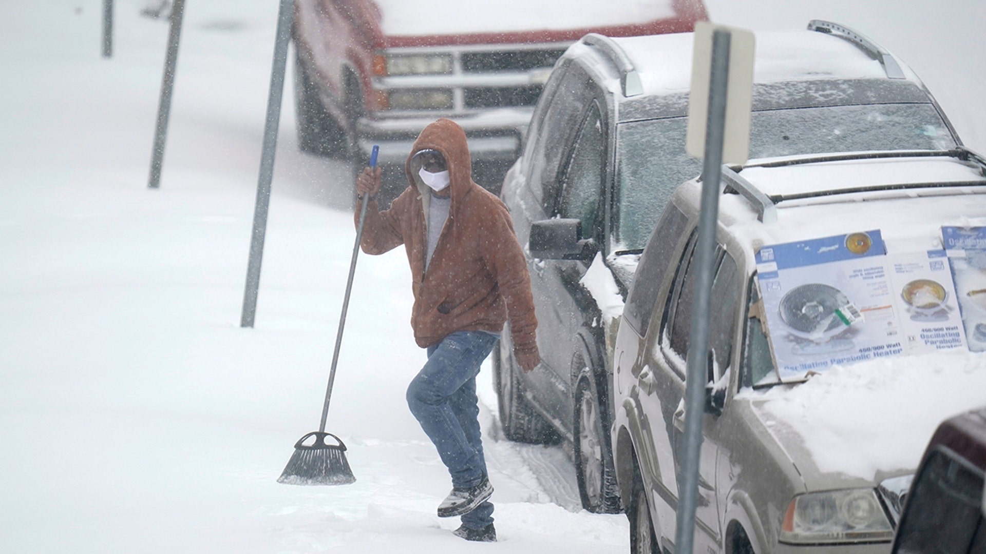 A person carries a broom after brushing snow off a car Monday, Feb. 15, 2021, in St. Louis. Missouri is being hit by a winter storm bringing snow and brutally cold temperatures.