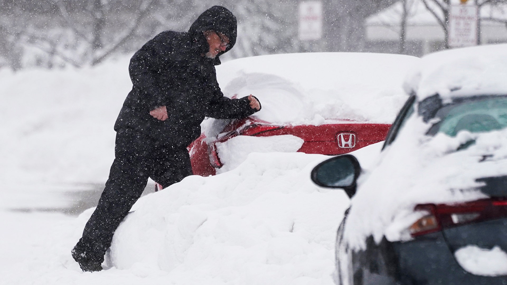 A man cleans the snow off of his car during a winter storm in Wheeling, Ill., Sunday, Jan. 31, 2021. (AP Photo/Nam Y. Huh)