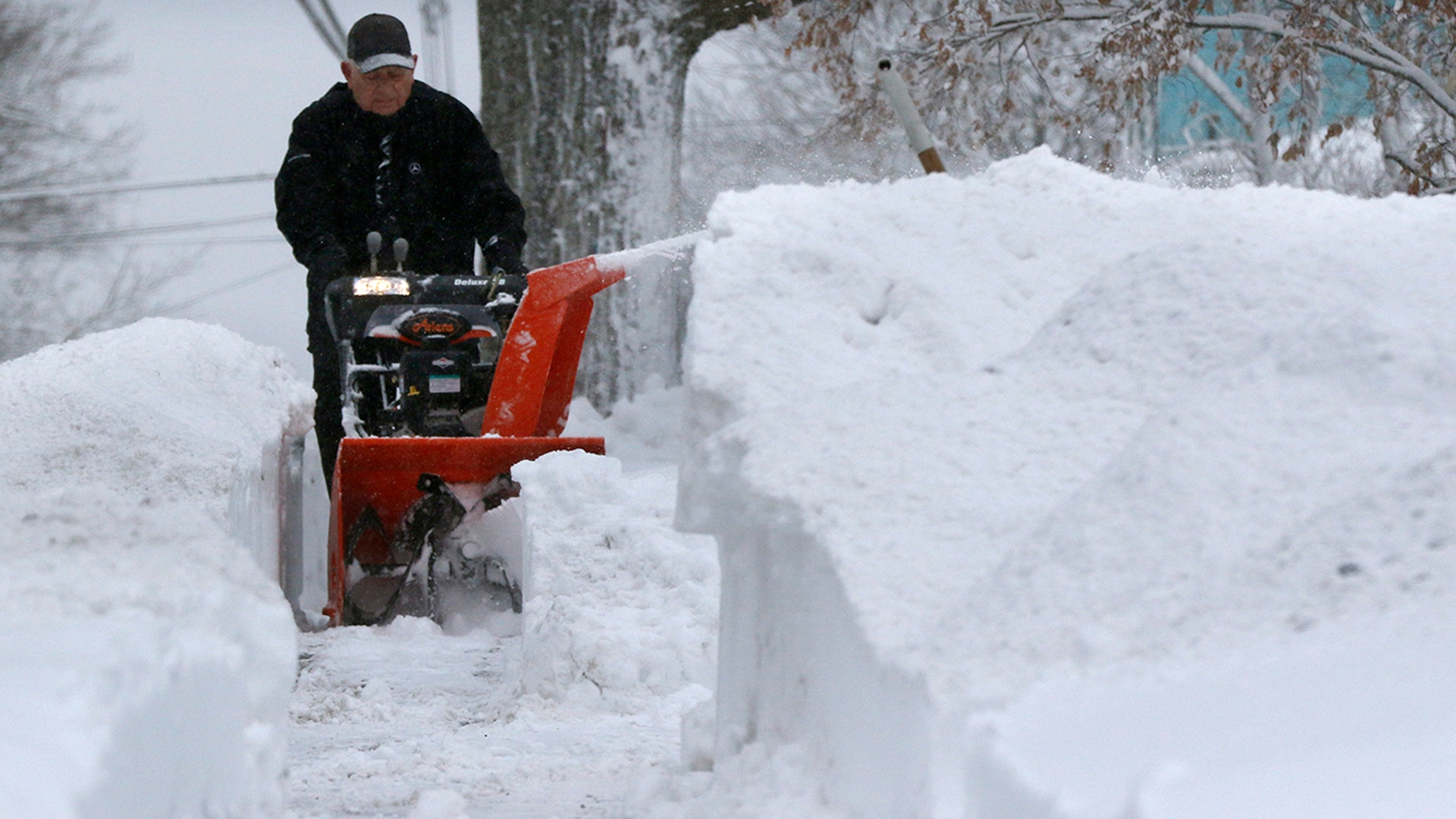 A man uses a snow thrower to clear a sidewalk after a snowstorm Tuesday, Feb. 2, 2021, in Marlborough, Mass.