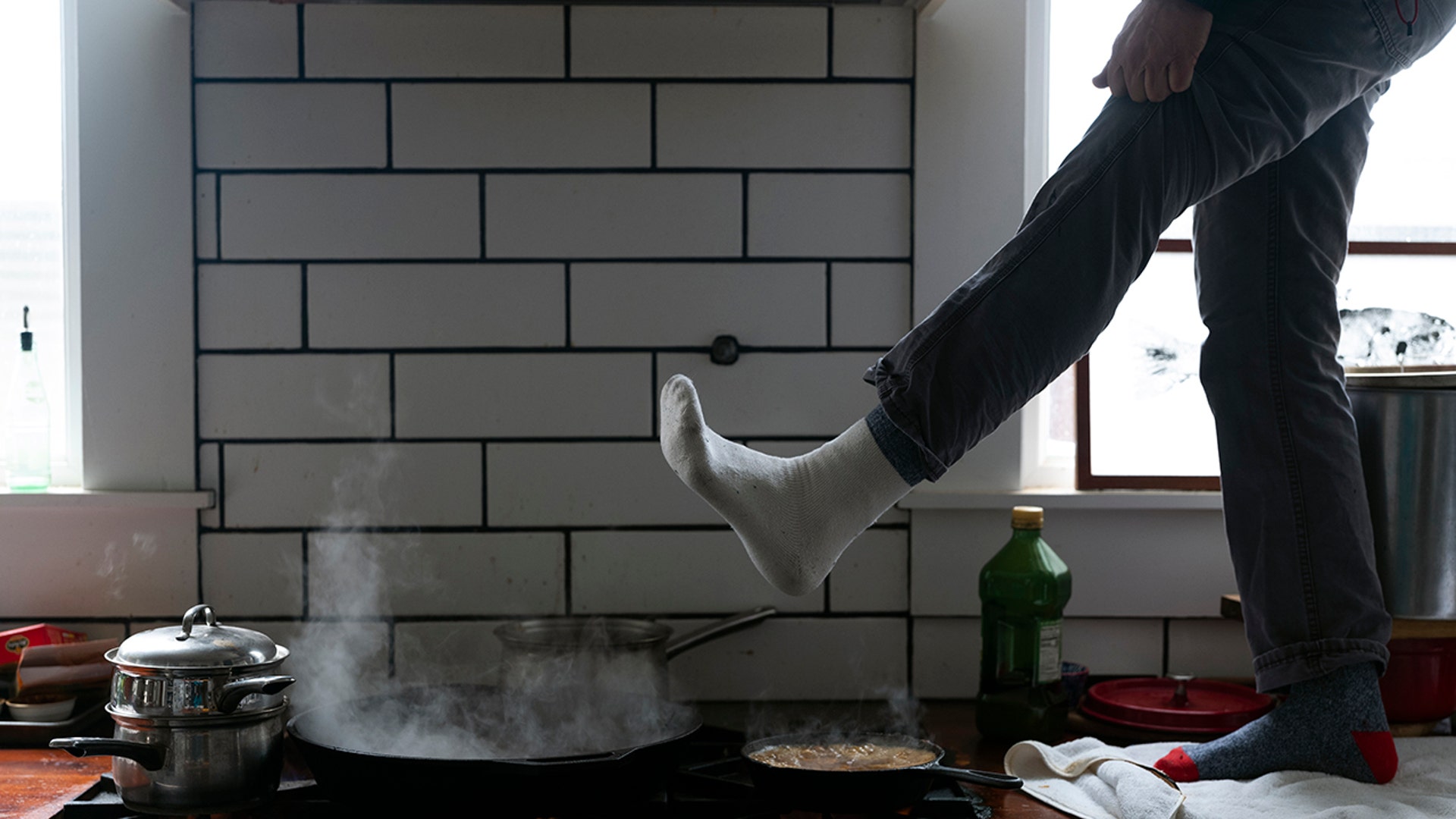 Jorge Sanhueza-Lyon stands on his kitchen counter to warm his feet over his gas stove Tuesday, Feb. 16, 2021, in Austin, Texas. Power was out for thousands of central Texas residents after temperatures dropped into the single digits when a snow storm hit the area on Sunday night.