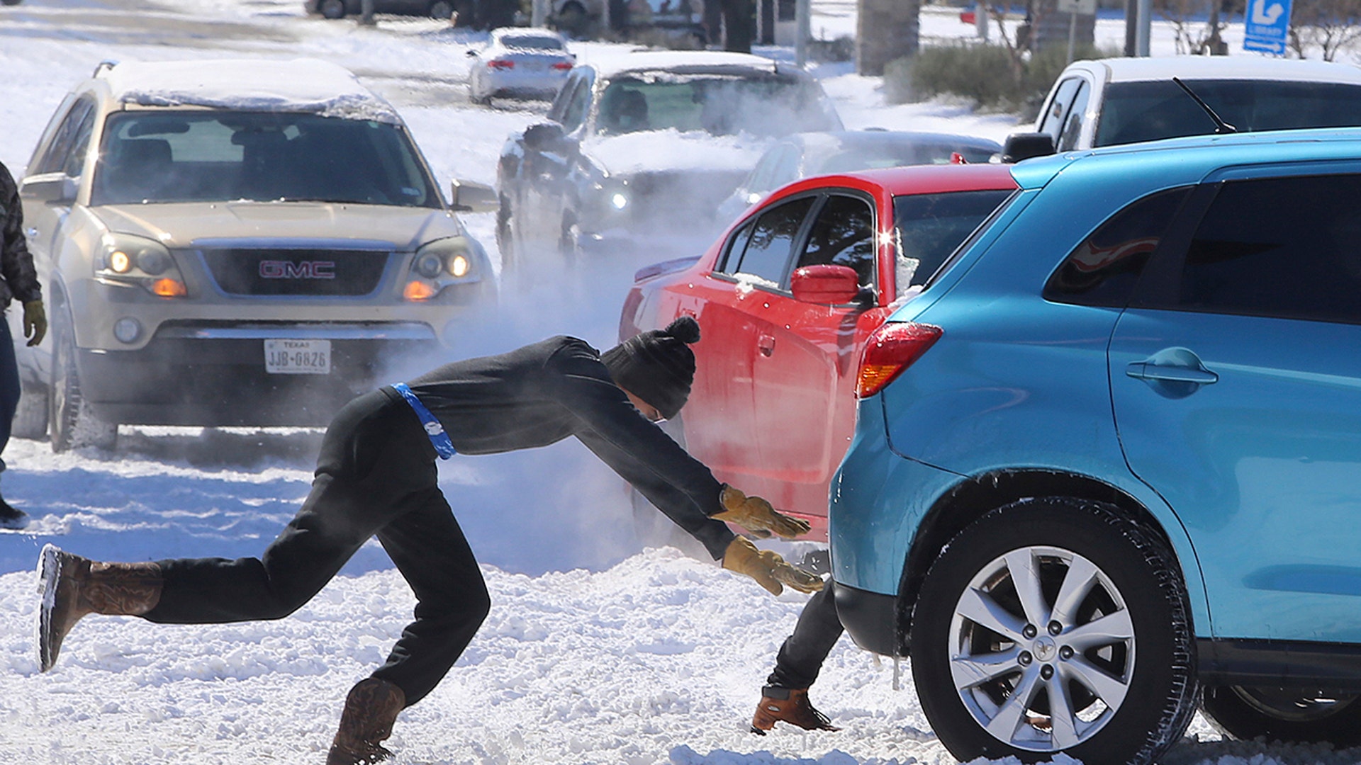 People push a car free after spinning out in the snow Monday, Feb. 15, 2021 in Waco, Texas. A winter storm that brought snow, ice and plunging temperatures across the southern Plains and caused a power emergency in Texas stretched its frigid fingers down to the Gulf Coast.