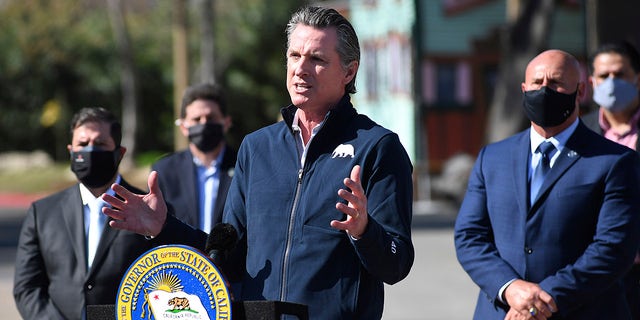 California Gov. Gavin Newsom, center, gestures in front of local officials while speaking about COVID-19 vaccines at the Fresno Fairgrounds, Wednesday, Feb. 10, 2021, in Fresno, Calif. (John Walker/The Fresno Bee via AP)