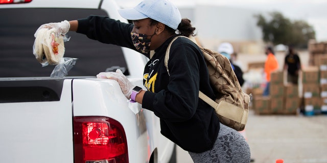 Volunteer Taiya Edwards, 18, places a pack of tortillas on a vehicle during the Neighborhood Super Site food distribution event organized by the Houston Food Bank and HISD, Sunday, Feb. 21, 2021, in Houston. (Marie D. De Jesús/Houston Chronicle via AP)