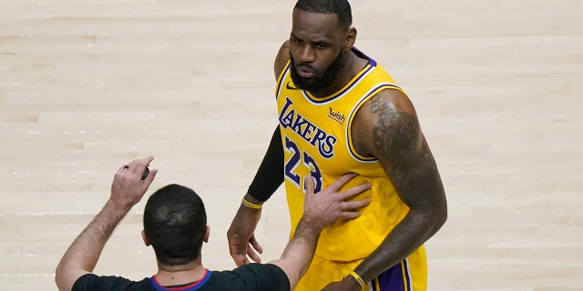 Los Angeles Lakers forward LeBron James, 23, is being held by an official while responding to a fan in the second half of an NBA basketball game against the Atlanta Hawks, Monday, February 1, 2021, in Atlanta.  (AP Photo / John Bazemore)