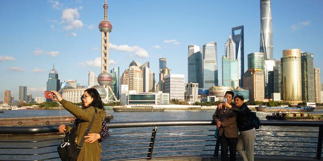 FILE: People take selfies of the Pudong skyline as they stand on the Bund in Shanghai, China. 