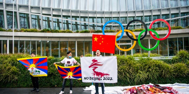 Protesters hold Tibetan flags during a protest against Beijing 2022 Winter Olympics by activists of the Tibetan Youth Association in Europe, in front of the International Olympic Committee, IOC, headquarters in Lausanne, Switzerland, Wednesday, Feb. 3, 2021. A coalition of 180 rights groups is calling for a boycott of next year's Beijing Winter Olympics tied to reported human rights abuses in China. The games are to open on February 4, 2022. (Jean-Christophe Bott/Keystone via AP)