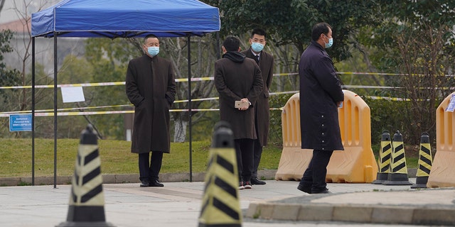 Security personnel watch a checkpoint into the cordoned off area where a World Health Organization team is staying at a hotel in central China's Hubei province on Thursday, Feb. 4, 2021. The WHO team is investigating the origins of the coronavirus pandemic in the province. (AP Photo/Ng Han Guan)