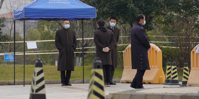 Security personnel watch a checkpoint into the cordoned off area where a World Health Organization team is staying at a hotel in central China's Hubei province on Thursday, Feb. 4, 2021. The WHO team is investigating the origins of the coronavirus pandemic in the province. (AP Photo/Ng Han Guan)