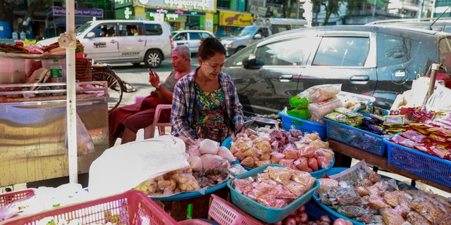 A street vendor checks his mobile phone in Yangon, Burma, Tuesday, Feb. 4, 2021. Burma's new military government has blocked access to Facebook as resistance to Monday's coup surged amid calls for civil disobedience to protest the ousting of the elected civilian government and its leader Aung San Suu Kyi. (AP Photo)