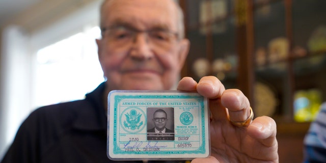 Paul Grisham is holding his 1968 Navy ID card, which was found in his wallet.  (Nelvin C. Cepeda / The San Diego Union-Tribune via AP)