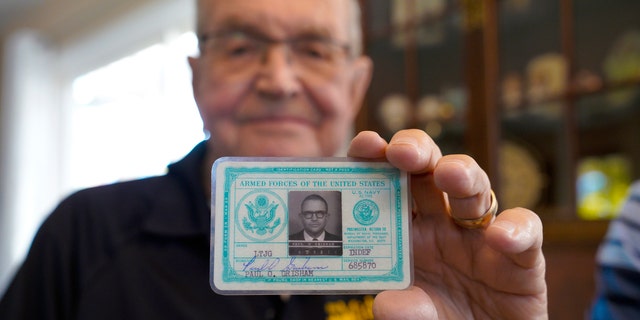 Paul Grisham holds his 1968 Navy ID card, which was found inside his wallet. (Nelvin C. Cepeda/The San Diego Union-Tribune via AP)
