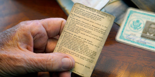 Paul Grisham holds one of the items that was found inside his wallet, an "Atomic, Biological, and Chemical Warfare Pocket Reference." (Nelvin C. Cepeda/The San Diego Union-Tribune via AP)