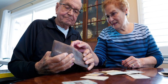 Paul Grisham and his wife Carole Salazar examine his wallet and the items in it when he lost the wallet in 1968 (Nelvin C. Cepeda / The San Diego Union-Tribune via AP)