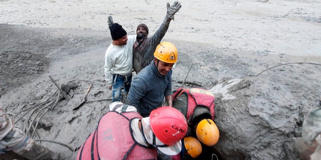 This photograph provided by Indo Tibetan Border Police (ITBP) shows a man reacting after he was pulled out from beneath the ground by ITBP personnel during rescue operations after a portion of Nanda Devi glacier broke off in Tapovan area of the northern state of Uttarakhand, India, Sunday, Feb.7, 2021. (Indo Tibetan Border Police via AP)