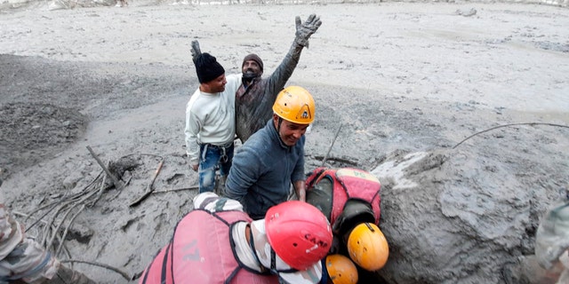 This photograph provided by Indo Tibetan Border Police (ITBP) shows a man reacting after he was pulled out from beneath the ground by ITBP personnel during rescue operations after a portion of Nanda Devi glacier broke off in Tapovan area of the northern state of Uttarakhand, India, Sunday, Feb.7, 2021. (Indo Tibetan Border Police via AP)