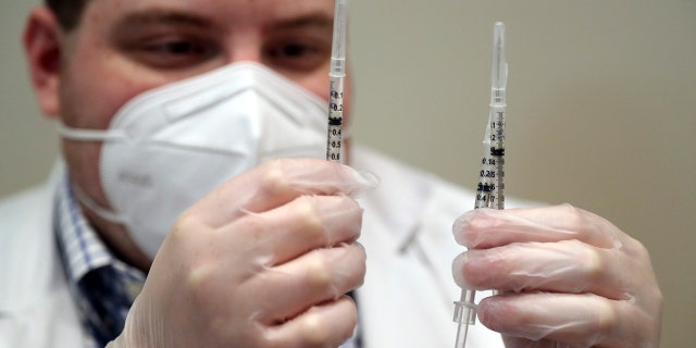Walgreens pharmacist Brandon Berger checks syringes before administering second doses of the Pfizer COVID-19 vaccine to seniors at John Knox Village, Tuesday, Feb. 9, 2021, in Pompano Beach, Fla. (Amy Beth Bennett/South Florida Sun-Sentinel via AP)