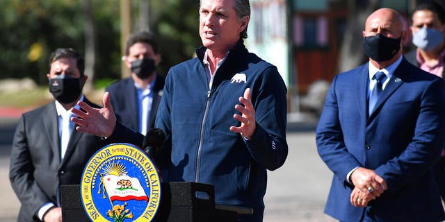 California Gov. Gavin Newsom, center, gestures in front of local officials while speaking about COVID-19 vaccines at the Fresno Fairgrounds, Wednesday, Feb. 10, 2021, in Fresno, Calif.