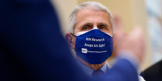 Dr. Anthony Fauci, director of the National Institute of Allergy and Infectious Diseases, listens as President Joe Biden speaks during a visit at the Viral Pathogenesis Laboratory at the National Institutes of Health (NIH), Thursday, Feb. 11, 2021, in Bethesda, Md. (AP Photo/Evan Vucci)