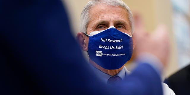 Dr. Anthony Fauci, director of the National Institute of Allergy and Infectious Diseases, listens as President Joe Biden speaks during a visit at the Viral Pathogenesis Laboratory at the National Institutes of Health (NIH), Thursday, Feb. 11, 2021, in Bethesda, Md. (AP Photo/Evan Vucci)