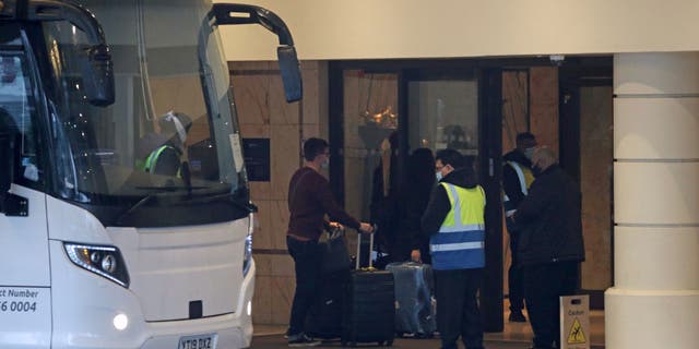 A coach delivers passengers to the Radisson Blu Edwardian Hotel, near Heathrow Airport, London, Monday Feb. 15, 2021 where they will remain during a 10 day quarantine period after returning to England from one of 33 "red list" countries. New regulations now in force require anyone who has been in a 'high-risk' location to enter England through a designated port and have pre-booked a package to stay at one of the Government's managed quarantine facilities. (Steve Parsons/PA via AP)