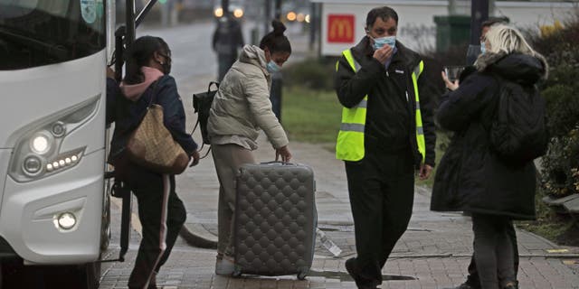 A coach delivers passengers to the Radisson Blu Edwardian Hotel, near Heathrow Airport, London, Monday Feb. 15, 2021 where they will remain during a 10 day quarantine period after returning to England from one of 33 "red list" countries. New regulations now in force require anyone who has been in a 'high-risk' location to enter England through a designated port and have pre-booked a package to stay at one of the Government's managed quarantine facilities. (Steve Parsons/PA via AP)