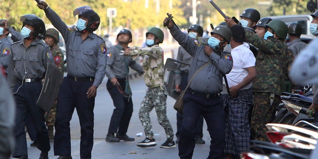 A policeman aims a slingshot towards an unknown target during a crackdown on anti-coup protesters holding a rally in front of the Myanmar Economic Bank in Mandalay, Burma on Monday, Feb. 15, 2021. (AP Photo)