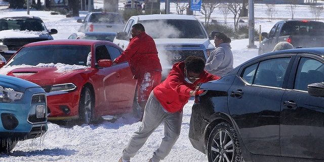 People push a car free after spinning out in the snow Monday, Feb. 15, 2021 in Waco, Texas. (Associated Press)