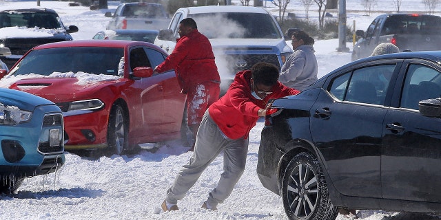People push a car free after spinning out in the snow Monday, Feb. 15, 2021 in Waco, Texas. (Associated Press)