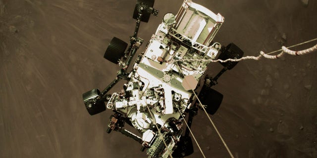 This Thursday, Feb. 18, 2021 photo provided by NASA shows the Perseverance rover lowered towards the surface of Mars during its powered descent. (NASA via AP)