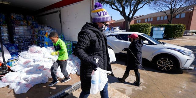 Marny Tackett, front, recreation superintendent with the City of Plano, Josiah Prince, 剩下, and Rebecca Hand, 对, Volunteer Resources Coordinator with the City of Plano, hand out water to waiting vehicles at Grace Church in Plano, 德州, 星期五, 二月. 19, 2021. In cooperation with the city, the church staff, volunteers, and city representatives have been handing water to those who have had their water shut off or pipes damaged in their homes as a result of the winter storm. (AP Photo/Tony Gutierrez)
