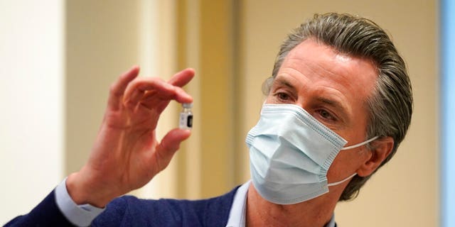 FILE: California Governor Gavin Newsom presents a vial of Pfizer-BioNTech COVID-19 vaccine at Kaiser Permanente Los Angeles Medical Center in Los Angeles. 