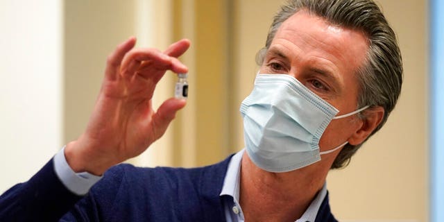 파일: 캘리포니아 정부. Gavin Newsom holds up a vial of the Pfizer-BioNTech COVID-19 vaccine at Kaiser Permanente Los Angeles Medical Center in Los Angeles.