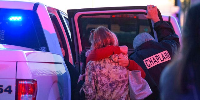 A Jefferson Parish Sheriff's Office Chaplain stands next to two women hugging at the scene of a multiple fatality shooting at the Jefferson Gun Outlet in Metairie, La. Saturday, Feb. 20, 2021. (Associated Press)