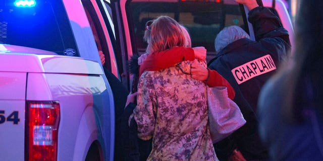 A Jefferson Parish Sheriff's Office Chaplain stands next to two women hugging at the scene of a multiple fatality shooting at the Jefferson Gun Outlet in Metairie, La. Saturday, Feb. 20, 2021. (Associated Press)