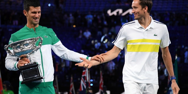 Serbia's Novak Djokovic, left, holds the Norman Brookes Challenge Cup as he talks with runner-up Russia's Daniil Medvedev after winning the men's singles final at the Australian Open tennis championship in Melbourne, Australia, Sunday, Feb. 21, 2021.(AP Photo/Andy Brownbill)