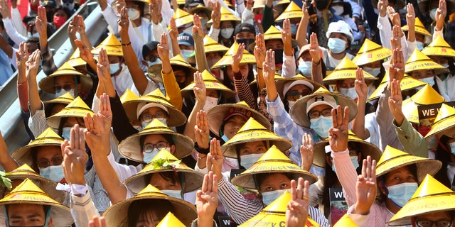 Anti-coup protesters flash the three-fingered salute during a rally near the Mandalay Railway Station in Mandalay, Burma Monday, Feb. 22, 2021. A call for a Monday general strike by demonstrators in Burma protesting the military's seizure of power has been met by the ruling junta with a thinly veiled threat to use lethal force, raising the possibility of major clashes. (AP Photo)