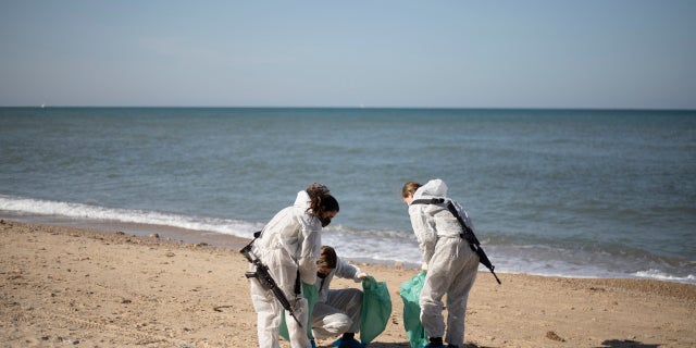Israeli soldiers wearing protective suits clean tar from a beach after an oil spill in the Mediterranean Sea in Sharon Beach Nature Reserve, near Gaash, Israel, Monday, Feb. 22, 2021. (AP Photo/Ariel Schalit)
