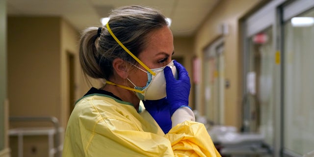 Registered Nurse Chrissie Burkhiser puts on personal protective equipment as she prepares to treat a COVID-19 patient in the emergency room at Scotland County Hospital in Memphis, Missouri (AP Photo / Jeff Roberson, File)