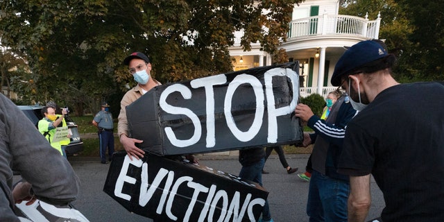 In this October 14, 2020 file photo, housing activists erect a sign outside the home of Massachusetts Governor Charlie Baker in Swampscott, Mass. (AP Photo / Michael Dwyer, File)