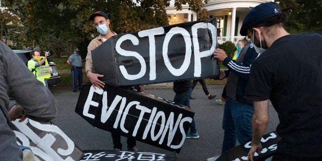 In this October 14, 2020 file photo, housing activists erect a sign outside the home of Massachusetts Governor Charlie Baker in Swampscott, Mass. (AP Photo / Michael Dwyer, File)