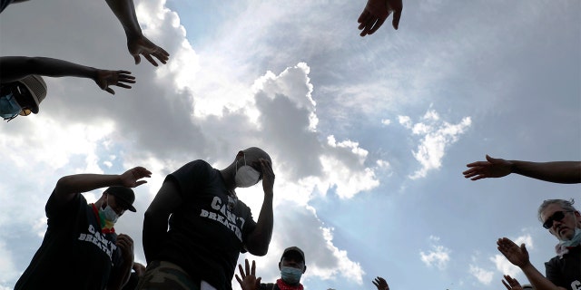 FILE - In this Saturday, June 6, 2020 file photo, Pastor Trevor Kinlock with Metropolitan Seventh-day Adventist Church, center, is prayed over as demonstrators protest in Washington, over the death of George Floyd. (AP Photo/Andrew Harnik)