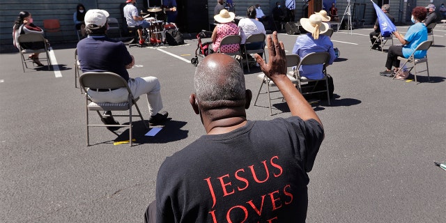 FILE - In this Sunday, July 19, 2020 file photo, church parishioners sit apart socially distanced at a prayer vigil for racial justice at Immaculate Conception Catholic Church in Seattle. (AP Photo/Elaine Thompson)