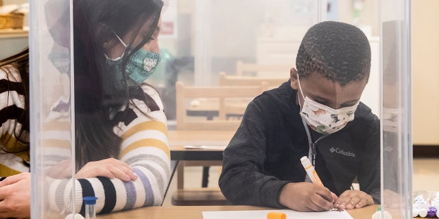 FILE - In this file photo from Jan.11, 2021, pre-kindergarten teacher Sarah McCarthy works with a student at Dawes Elementary in Chicago.  (Ashlee Rezin Garcia / Chicago Sun-Times via AP, Pool, File)