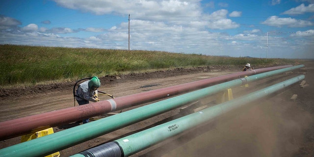 A construction worker specializing in pipe-laying sandblasts a section of pipeline on July 25, 2013 outside Watford City, North Dakota. North Dakota is currently experiencing an oil boom, creating thousands of jobs throughout the state and billions of dollars in new state revenue. Local two-lane roads that are used to access drill sites have taken a beating due to the unprecedented amount of traffic. Pipelines are being constructed across the state in part to streamline the movement of oil from drill sites to train depots and oil refineries.