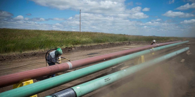 A construction worker specializing in piping sandblasting a section of pipeline July 25, 2013 outside Watford City, North Dakota. North Dakota is currently experiencing an oil boom, creating thousands of jobs statewide and billions of dollars in new revenue for the state. The local two-lane roads that are used to access the drilling sites have suffered a severe blow due to the unprecedented amount of traffic. Pipelines are being built statewide in part to streamline the movement of oil from drilling sites to train depots and oil refineries.