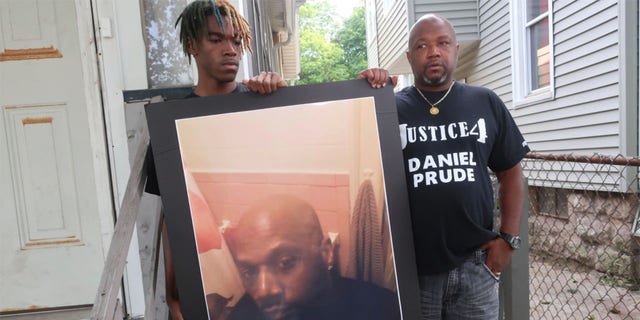 FILE - In this September 3, 2020 file photo, Joe Prude, brother of Daniel Prude, right, and his son Armin stand with a photo of Daniel Prude in Rochester, NY (AP Photo / Ted Shaffre, file)