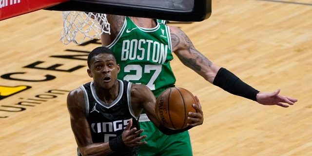 Sacramento Kings guard De'Aaron Fox, left, goes to the basket against Boston Celtics center Daniel Theis during the first quarter of an NBA basketball game in Sacramento, Calif., Wednesday, Feb. 3, 2021. (AP Photo/Rich Pedroncelli)